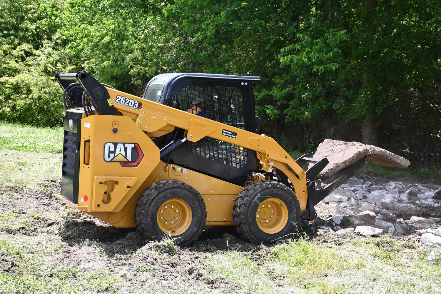 Rented CAT skid steer moving boulders